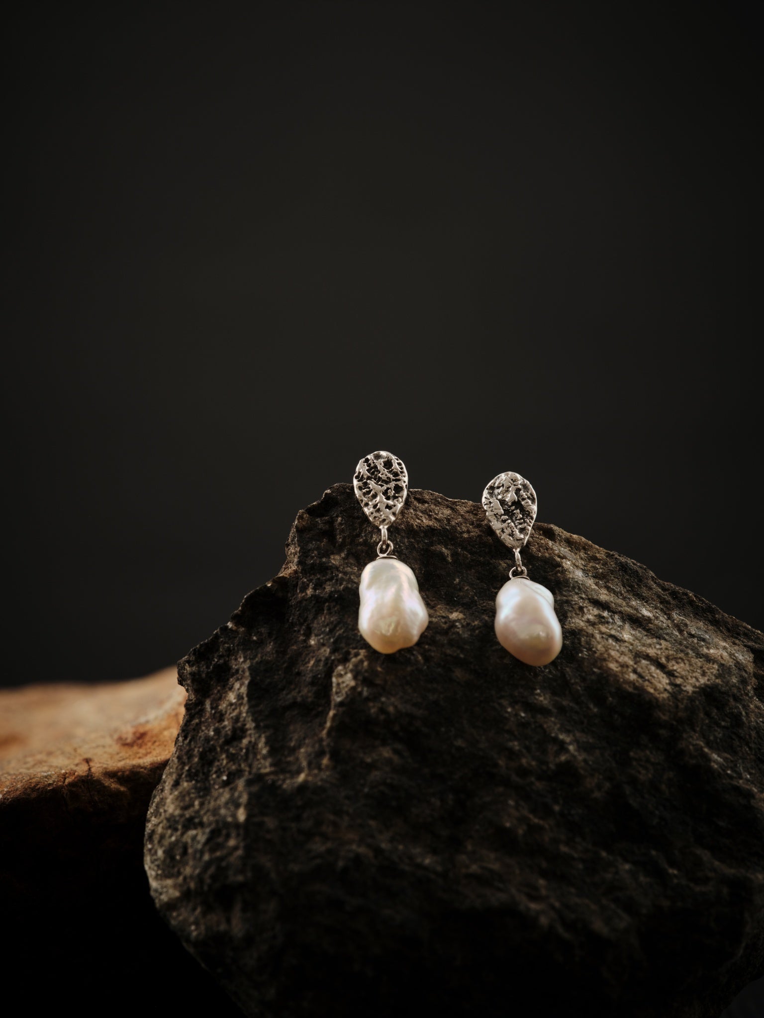 Boucles d'oreilles formées en deux parties. La partie du haut est en argent et en forme de goutte est reliée à la partie du bas qui est une perle keshi blanche.