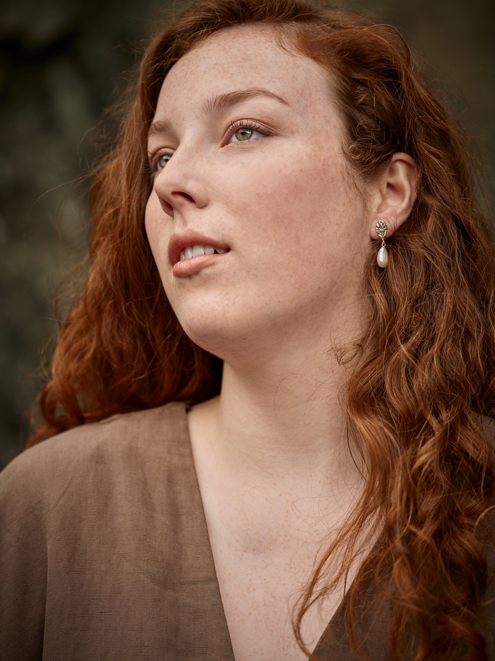 Portrait 3/4 d'une femme portant des boucles d'oreilles en argent avec une perle blanche